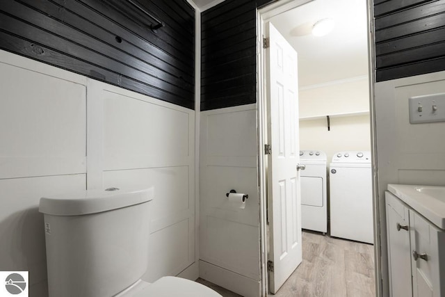 bathroom with washer and clothes dryer, hardwood / wood-style floors, vanity, ornamental molding, and toilet