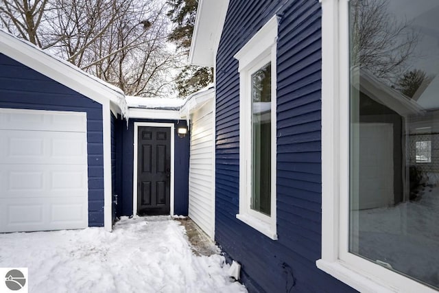 snow covered property with a garage