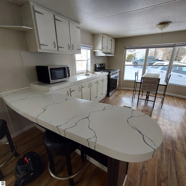 kitchen with white cabinetry, sink, stainless steel appliances, and kitchen peninsula