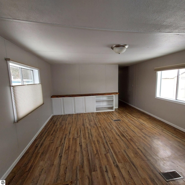 spare room featuring dark wood-type flooring and a textured ceiling