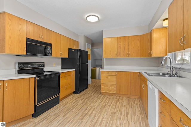 kitchen with sink, black appliances, and light hardwood / wood-style floors