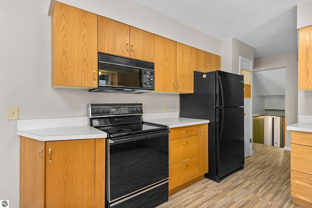 kitchen featuring light hardwood / wood-style floors, a textured ceiling, and black appliances