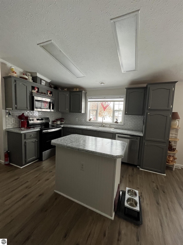 kitchen with sink, a center island, appliances with stainless steel finishes, dark hardwood / wood-style flooring, and gray cabinets