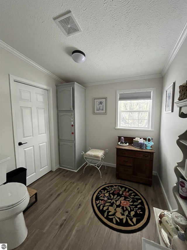 interior space with hardwood / wood-style flooring, crown molding, a textured ceiling, and toilet