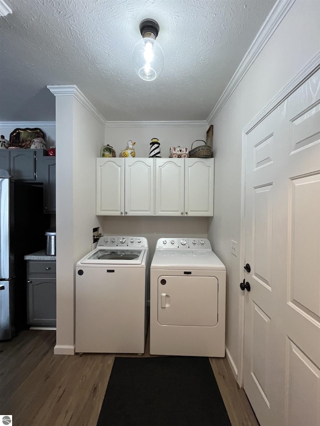 laundry area with cabinets, washing machine and dryer, dark hardwood / wood-style floors, and ornamental molding