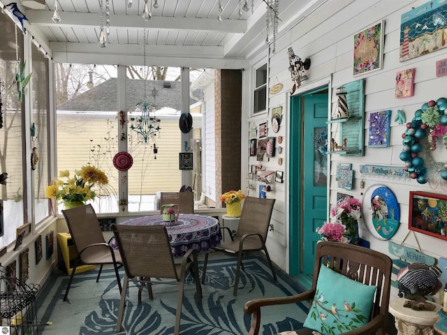 sunroom / solarium featuring beamed ceiling and plenty of natural light