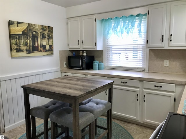 kitchen with backsplash, radiator heating unit, wooden walls, and white cabinets