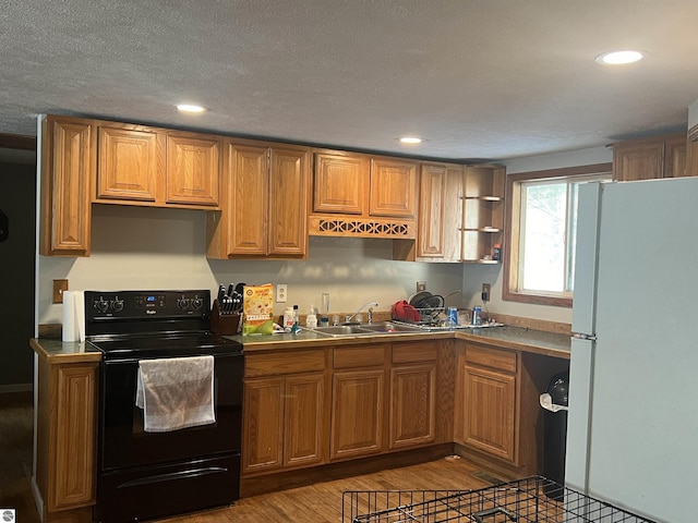 kitchen featuring wood-type flooring, sink, white refrigerator, black electric range, and a textured ceiling