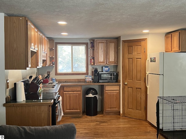 kitchen with a textured ceiling, light hardwood / wood-style flooring, and black appliances