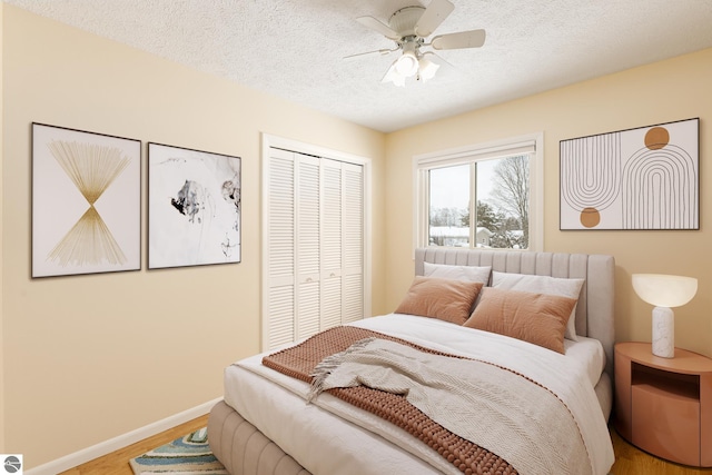 bedroom with ceiling fan, light hardwood / wood-style floors, a closet, and a textured ceiling