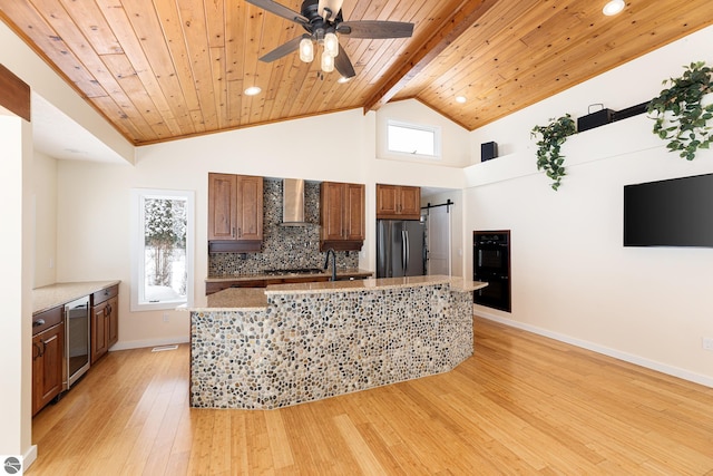 kitchen with backsplash, wood ceiling, stainless steel appliances, a barn door, and wall chimney range hood