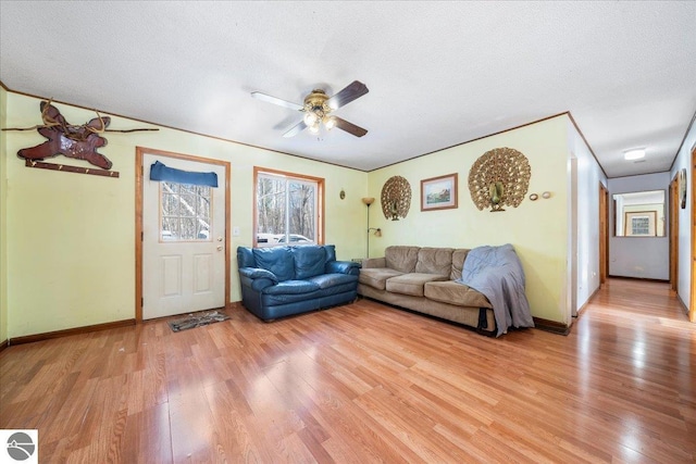 living room with ceiling fan, a textured ceiling, and light wood-type flooring