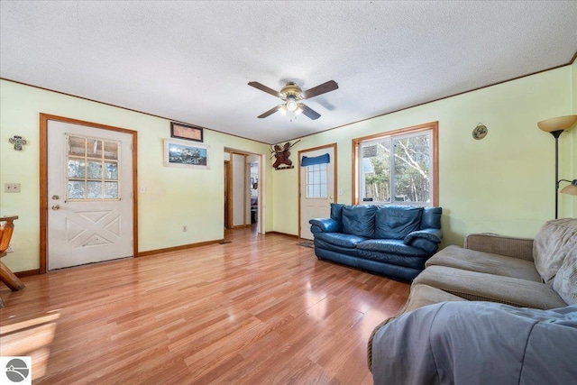 living room with ceiling fan, a textured ceiling, and light wood-type flooring