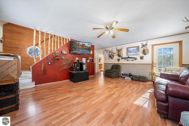 living room with wood-type flooring, ceiling fan, and a textured ceiling