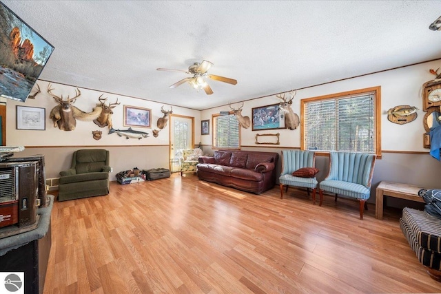 living room with ceiling fan, a textured ceiling, and light hardwood / wood-style flooring