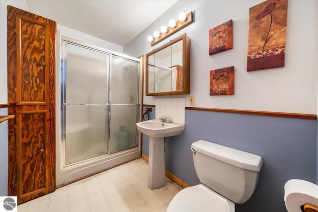 bathroom with a shower with door and toilet