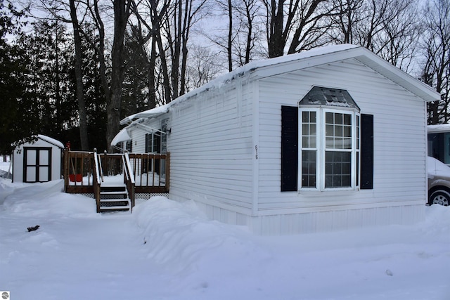 view of snow covered exterior featuring a shed and a deck