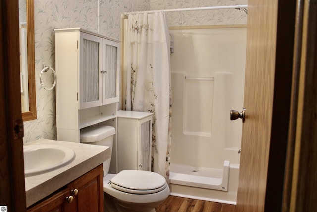 bathroom featuring vanity, wood-type flooring, toilet, and walk in shower