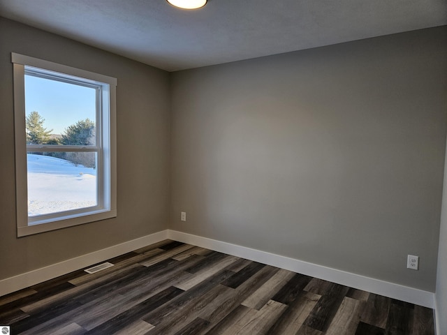 9872 Cushman Ct, Williamsburg, MI 49690 - empty room featuring baseboards, dark wood-style flooring, visible vents, and plenty of natural light
