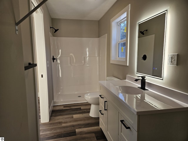 bathroom with hardwood / wood-style flooring, vanity, a shower, and toilet