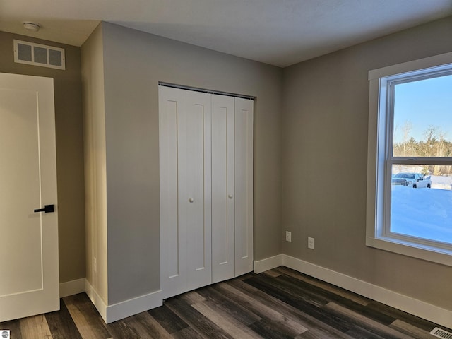 unfurnished bedroom with dark hardwood / wood-style floors and a closet