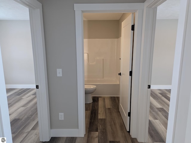 bathroom with hardwood / wood-style flooring, toilet, and shower / bathing tub combination