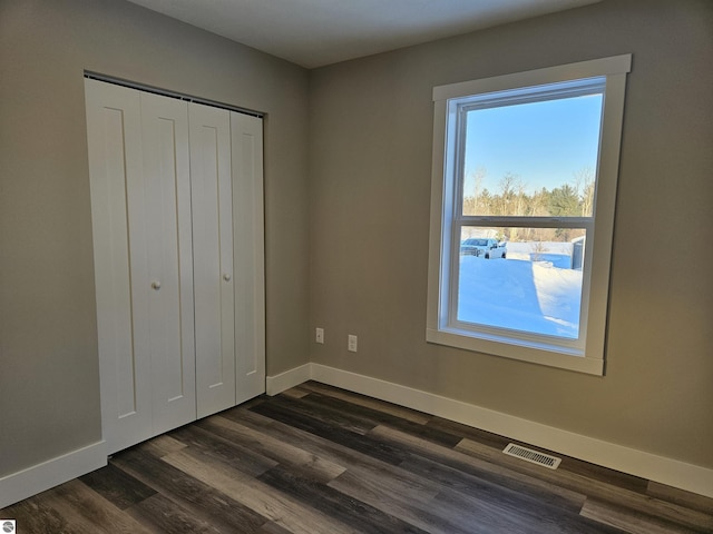 unfurnished bedroom featuring dark hardwood / wood-style floors and a closet