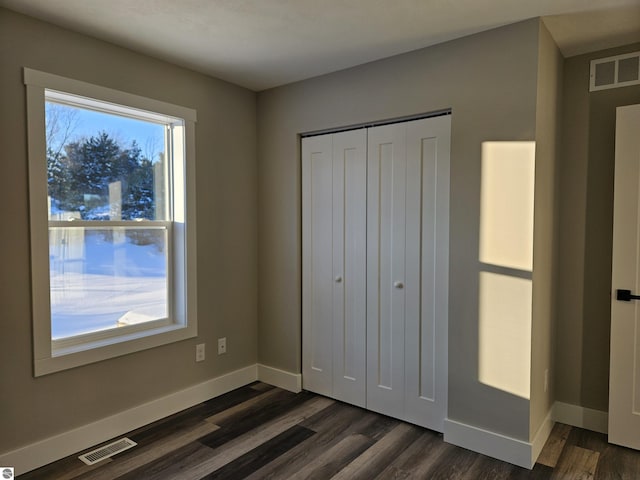 unfurnished bedroom featuring dark hardwood / wood-style floors and a closet