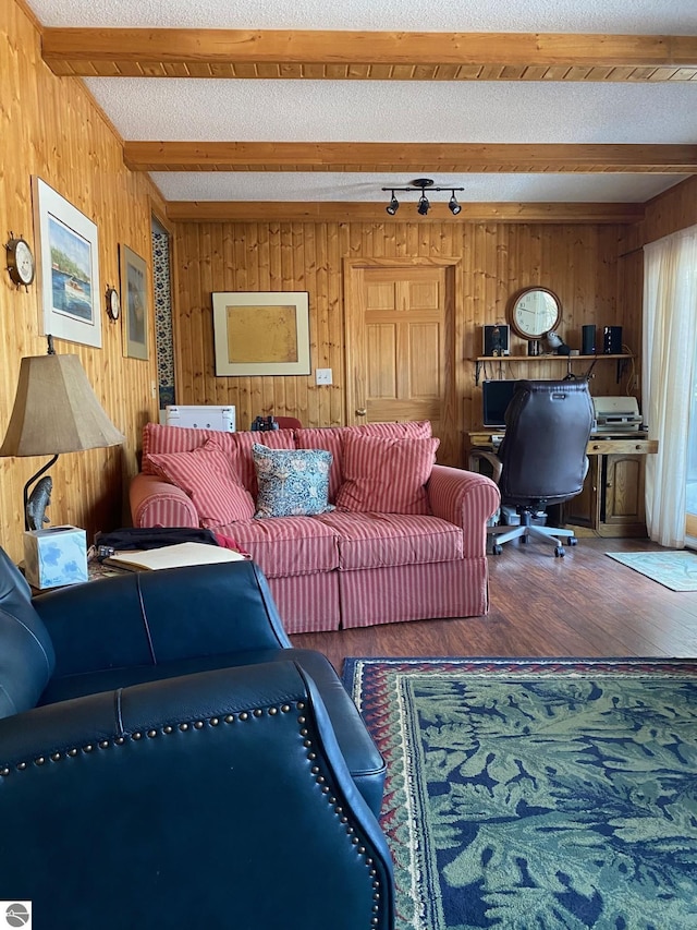 living room with beamed ceiling, hardwood / wood-style floors, a textured ceiling, and wooden walls