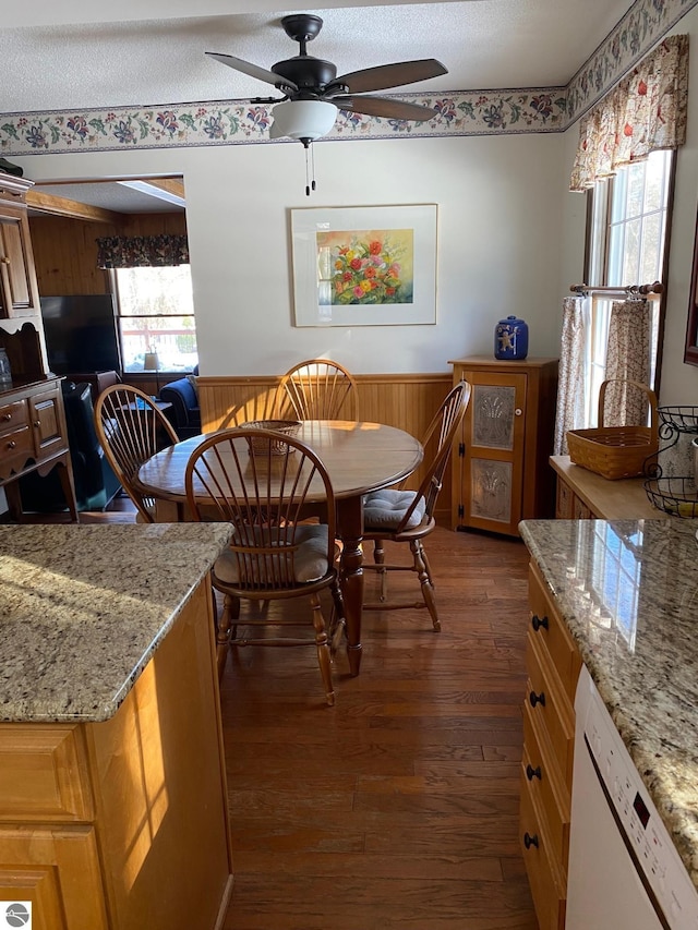 dining room with ceiling fan, dark wood-type flooring, wooden walls, and a textured ceiling