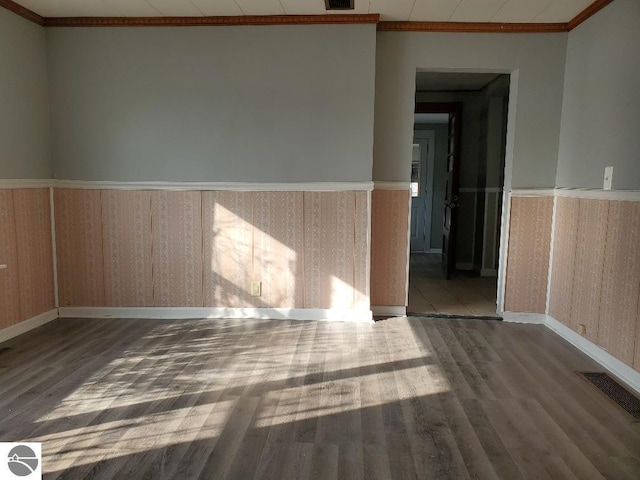 empty room with ornamental molding and wood-type flooring