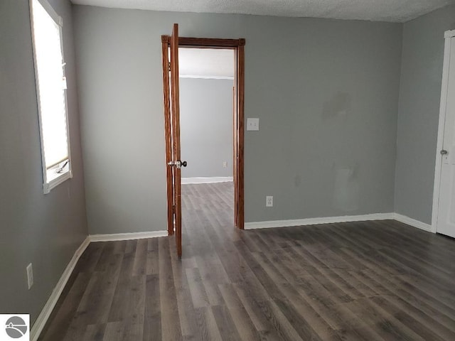 spare room with a textured ceiling and dark hardwood / wood-style flooring