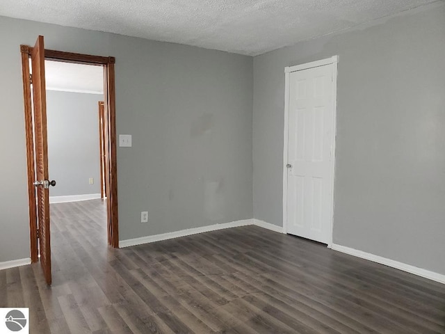 unfurnished room featuring dark wood-type flooring and a textured ceiling