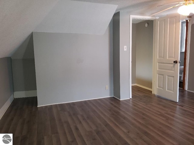 additional living space with lofted ceiling, a textured ceiling, dark hardwood / wood-style floors, and ceiling fan