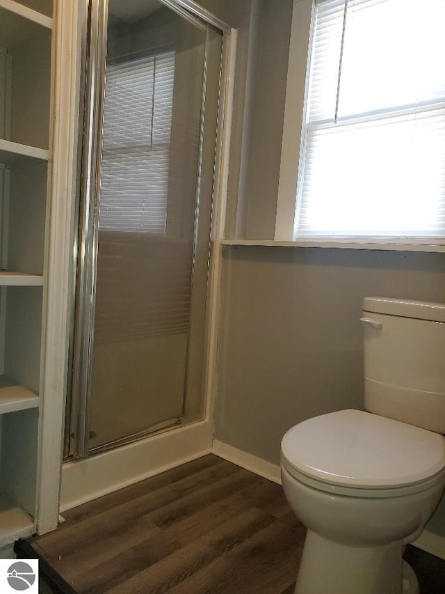 bathroom with wood-type flooring, a shower with door, and toilet