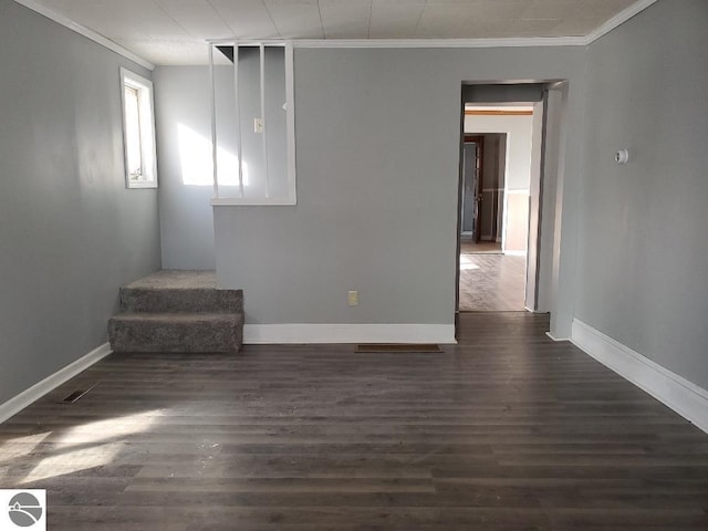 empty room featuring dark wood-type flooring and ornamental molding