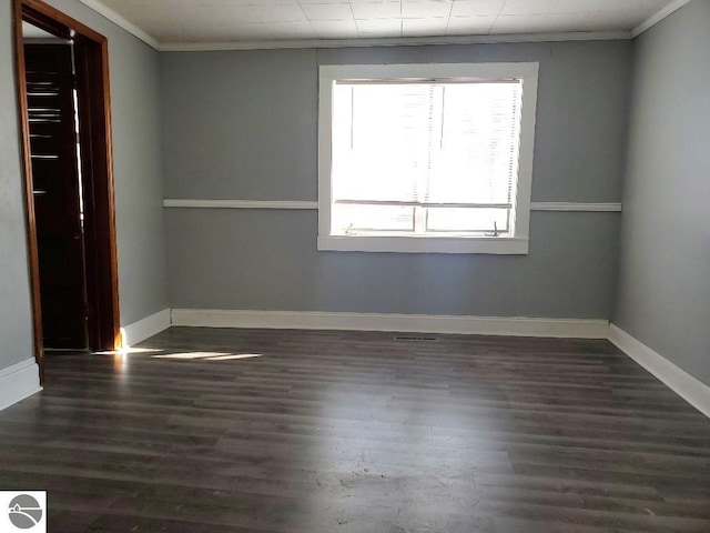 empty room featuring crown molding and dark wood-type flooring