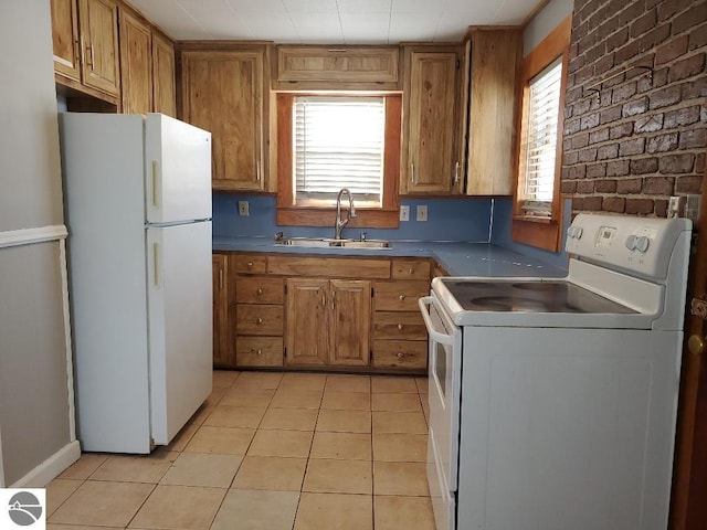 kitchen with white appliances, brick wall, sink, and light tile patterned floors