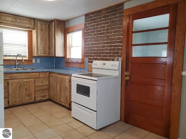 kitchen with sink, white electric range, light tile patterned floors, and brick wall