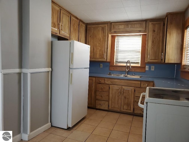 kitchen featuring white appliances, sink, and light tile patterned floors