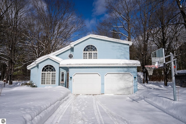 snow covered front of house featuring a garage