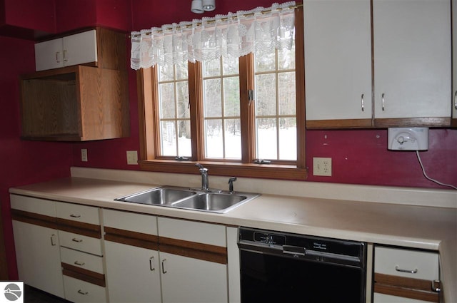 kitchen with a sink, black dishwasher, white cabinets, and light countertops