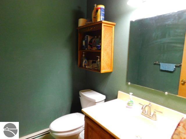 half bathroom featuring a baseboard radiator, vanity, and toilet