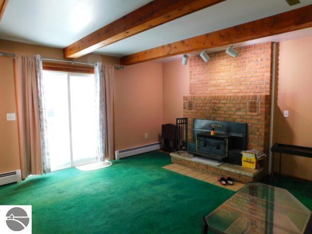 carpeted living area featuring baseboard heating, beam ceiling, and baseboards