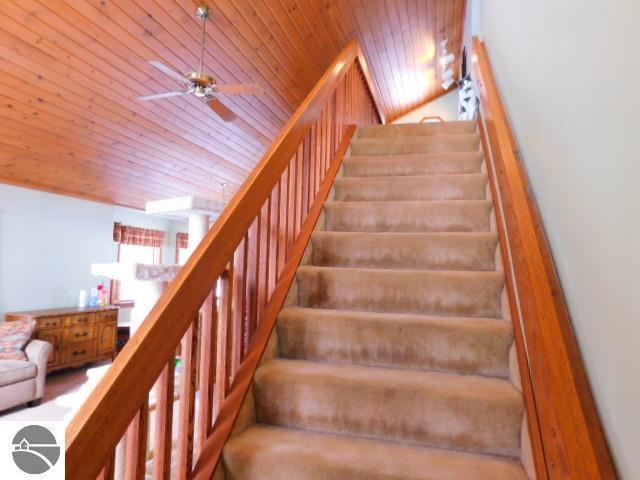 staircase with wood ceiling and a ceiling fan