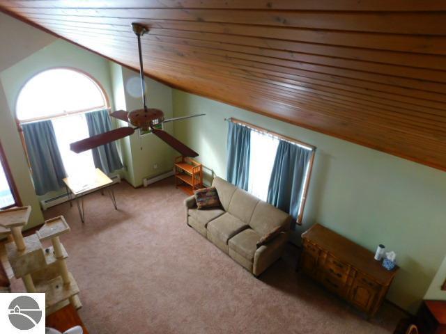 living area with a ceiling fan, lofted ceiling, wooden ceiling, carpet flooring, and a baseboard heating unit