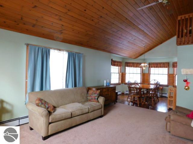 carpeted living room featuring lofted ceiling, baseboard heating, and wooden ceiling