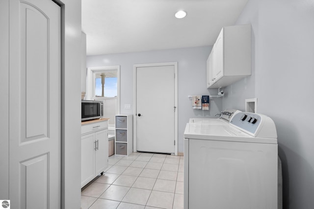 washroom with light tile patterned floors, washing machine and dryer, and cabinets