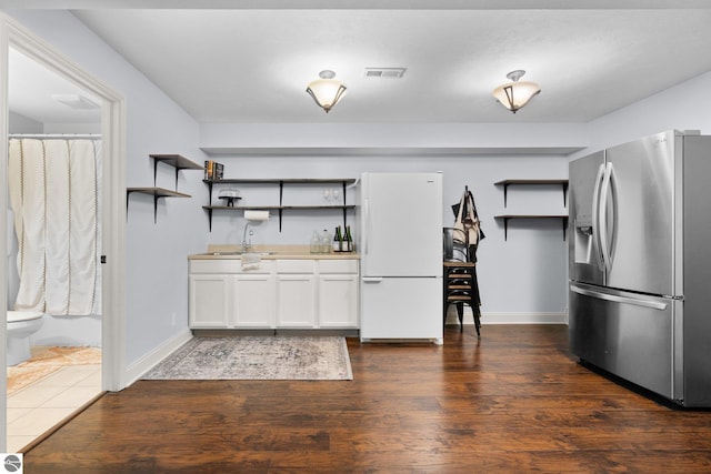 kitchen featuring sink, stainless steel fridge, white refrigerator, white cabinets, and dark hardwood / wood-style flooring