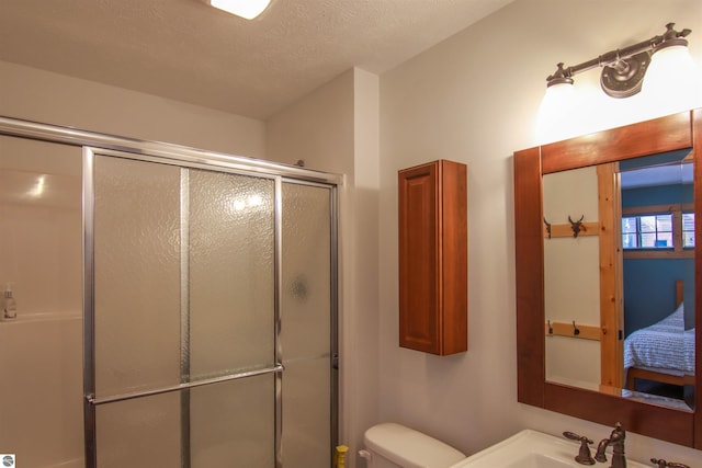 bathroom featuring toilet, sink, a textured ceiling, and a shower with shower door